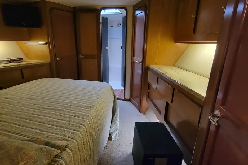  Yacht Photos Pics 1986 Ocean Yachts 55 Super Sport bedroom with ensuite bathroom, wooden cabinetry, and cozy lighting.