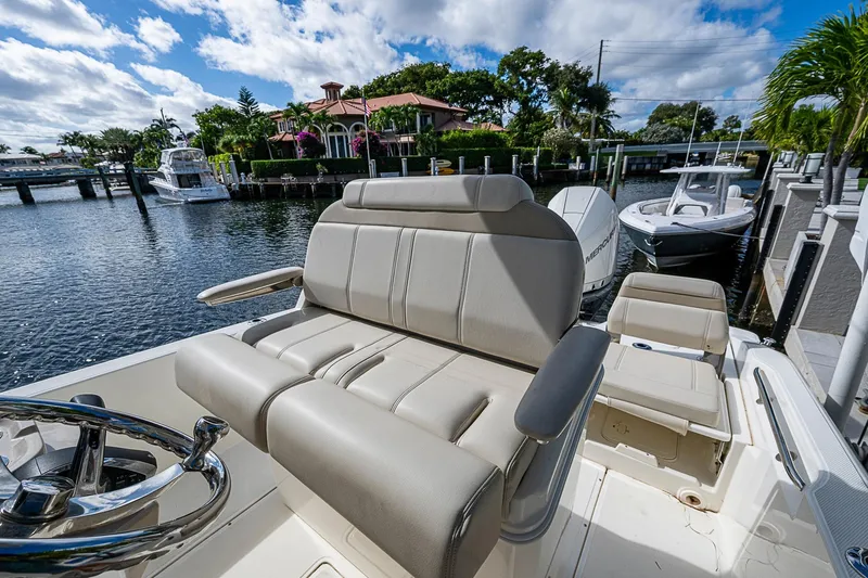 Yacht Photos Pics 2023 Boston Whaler 250 Dauntless boat interior with seating, docked by waterfront homes.