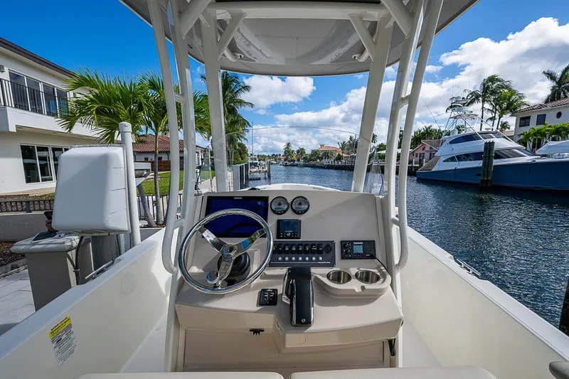  Yacht Photos Pics 2023 Boston Whaler 250 Dauntless boat helm with waterfront view, palm trees, and luxury yachts.