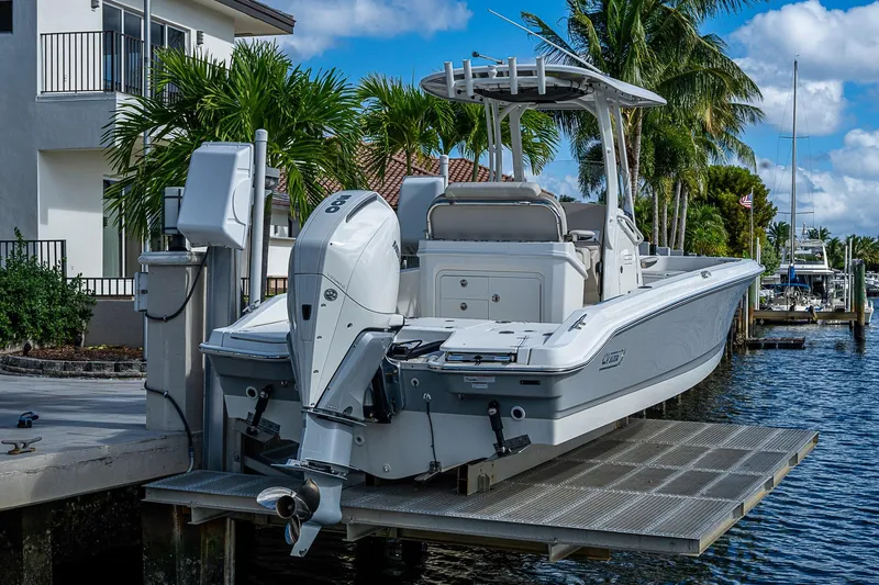  Yacht Photos Pics 2023 Boston Whaler 250 Dauntless boat docked by waterfront home with palm trees.