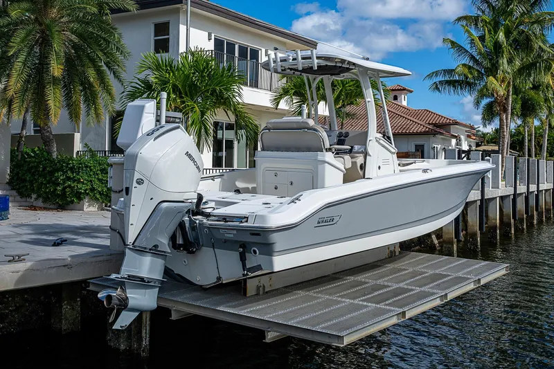  Yacht Photos Pics 2023 Boston Whaler 250 Dauntless boat docked by waterfront home with palm trees.