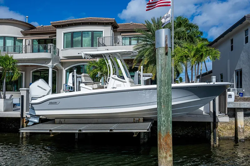  Yacht Photos Pics 2023 Boston Whaler 250 Dauntless boat docked by luxury waterfront homes.