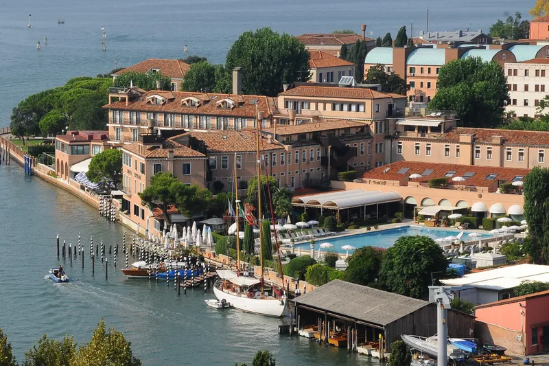 Barinia Yacht Photos Pics Aerial view of a luxurious waterfront hotel with a 1950 MOLLICH Sailing boat docked nearby.