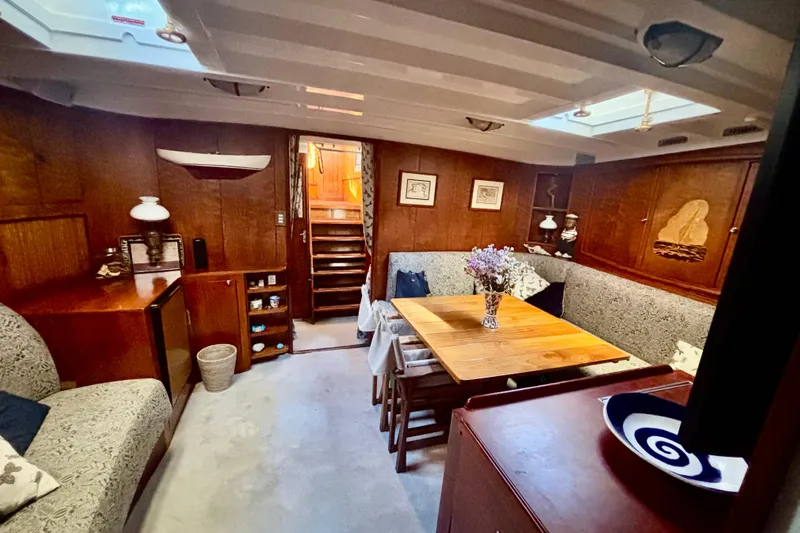Barinia Yacht Photos Pics 1950 MOLLICH Sailing yacht interior with wooden decor, cozy seating, and dining area.