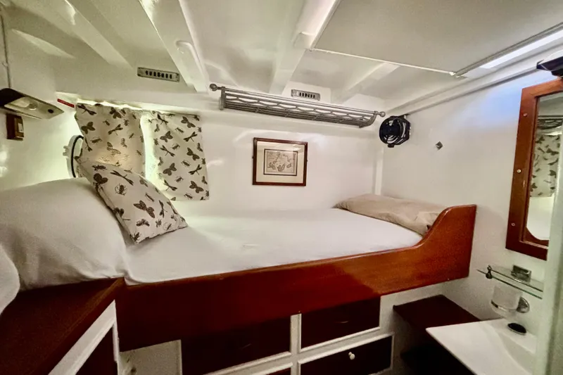 Barinia Yacht Photos Pics 1950 MOLLICH Sailing boat cabin with cozy bed, butterfly curtains, and wooden accents.
