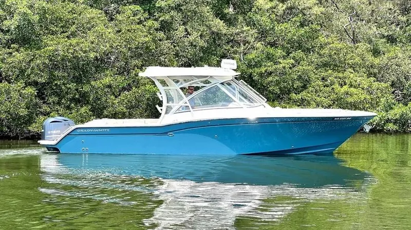  Yacht Photos Pics 2019 Grady-White Freedom 325 boat on calm water, surrounded by lush greenery.