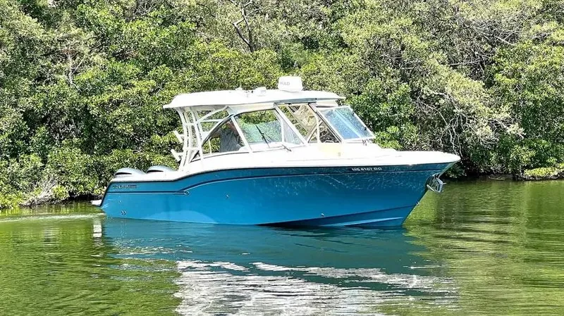 Yacht Photos Pics 2019 Grady-White Freedom 325 boat on calm water, surrounded by lush greenery.