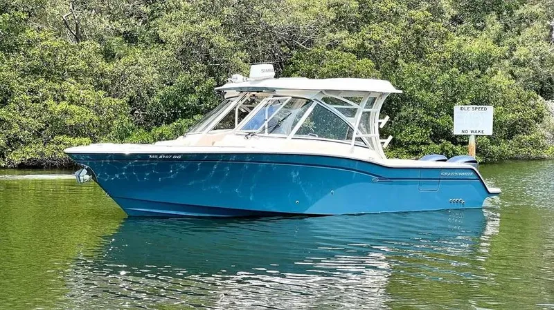  Yacht Photos Pics 2019 Grady-White Freedom 325 boat on calm water, surrounded by lush greenery.