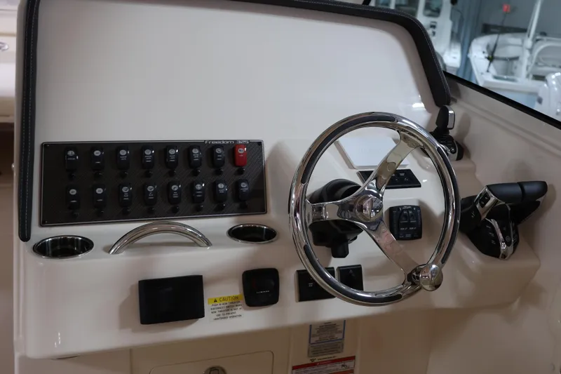  Yacht Photos Pics Helm of 2026 Grady-White Freedom 325 boat with steering wheel and control panel.