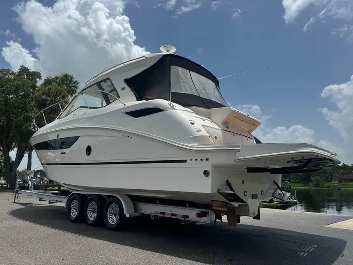  Yacht Photos Pics 2017 Sea Ray Sundancer 350 Coupe on trailer, parked near water under a cloudy sky.
