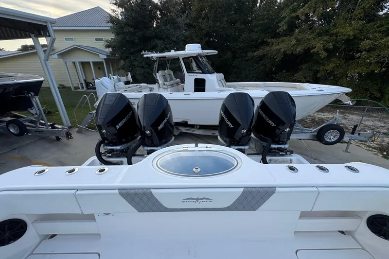  Yacht Photos Pics 2021 Invincible 35' Catamaran with four Mercury outboard engines, parked near a house.