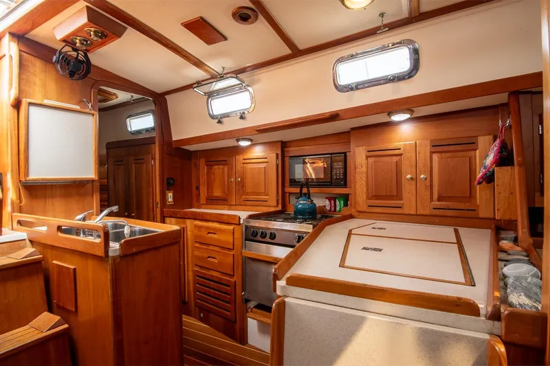 Jericho Yacht Photos Pics Cozy wooden interior of 2002 Tartan 4100 sailboat kitchen with stove and sink.