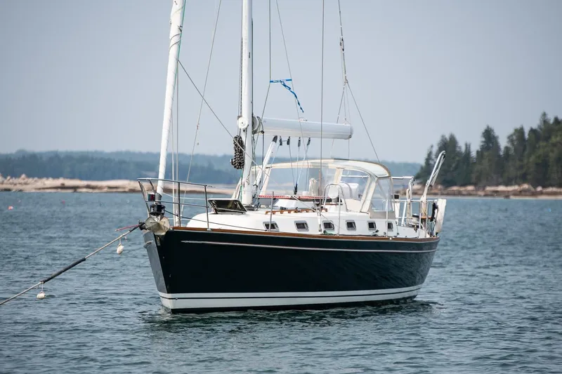 Jericho Yacht Photos Pics Sailboat Tartan 4100, 2002 model, anchored in calm waters with forested shoreline.