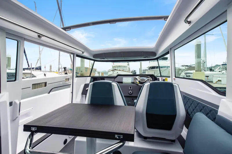 Egret Yacht Photos Pics Interior of 2023 Axopar 37 boat with modern seating and table, docked at marina.