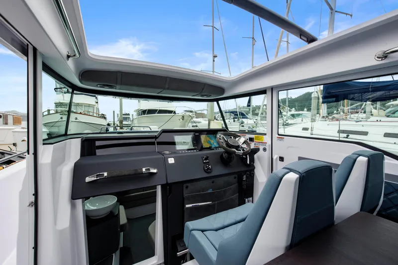 Egret Yacht Photos Pics 2023 Axopar 37 boat interior with modern dashboard and blue seating in marina.