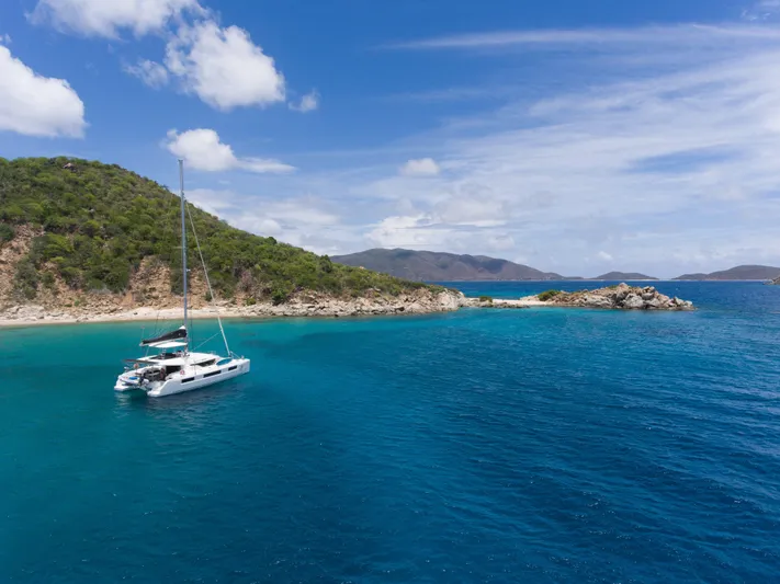 Echo Yacht Photos Pics 2023 Lagoon 50 catamaran anchored in a serene tropical bay with clear blue waters.