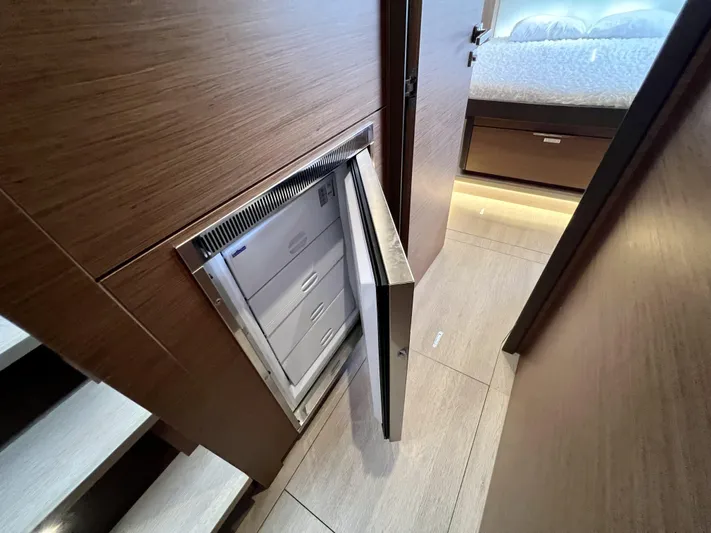Echo Yacht Photos Pics 2023 Lagoon 50 yacht interior with open built-in refrigerator, wooden finish, and visible bedroom.