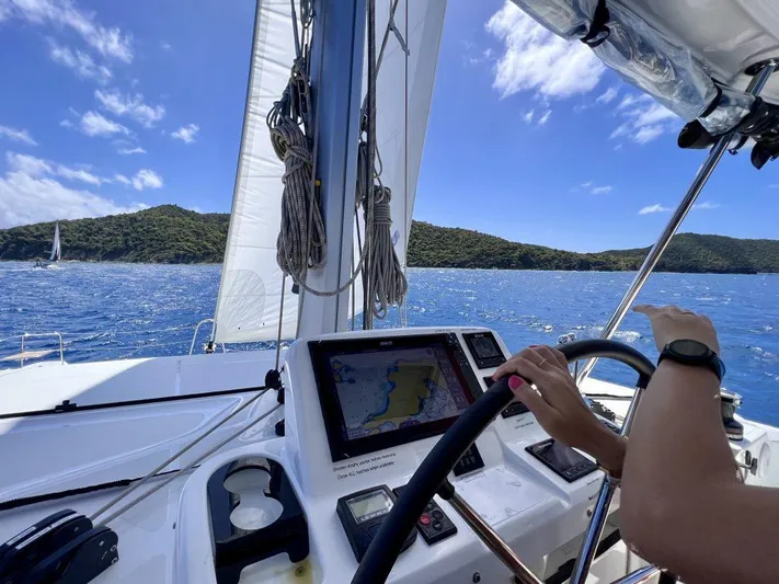 Echo Yacht Photos Pics 2023 Lagoon 50 yacht sailing with navigation system, blue sea, and distant islands.