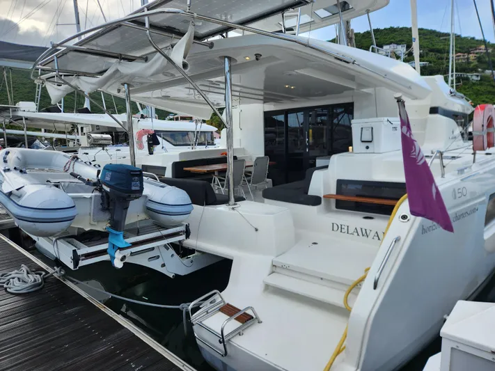 Echo Yacht Photos Pics 2023 Lagoon 50 catamaran docked, featuring a spacious deck and attached dinghy.