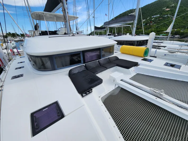 Echo Yacht Photos Pics 2023 Lagoon 50 catamaran with spacious deck, black seating, and scenic marina backdrop.