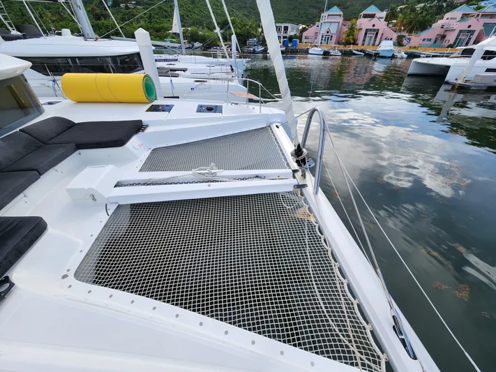 Echo Yacht Photos Pics 2023 Lagoon 50 catamaran with netted deck, docked in a scenic marina.