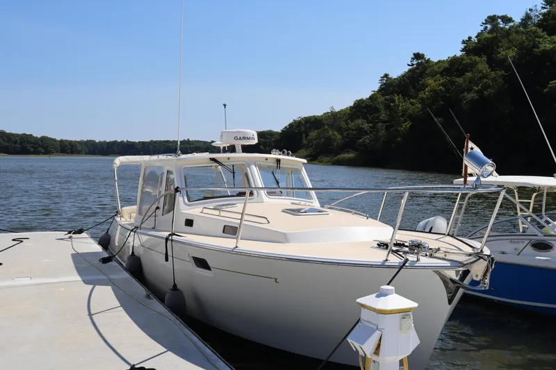 Rambler VIII Yacht Photos Pics 2013 MJM 36z Downeast boat docked by a scenic riverbank.