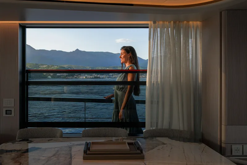  Yacht Photos Pics Woman enjoying view from Absolute Navetta 62 yacht, 2026 model, with scenic mountain backdrop.