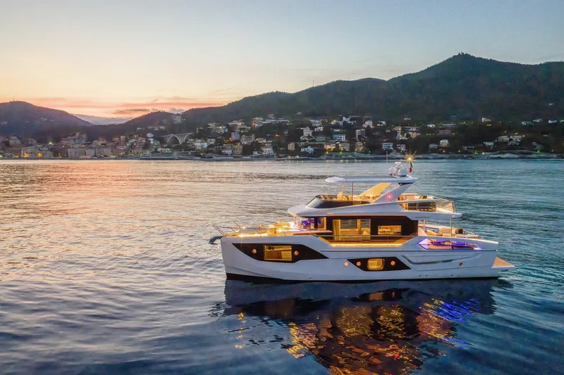  Yacht Photos Pics Luxurious 2026 Absolute Navetta 62 yacht at sunset, near a coastal town.