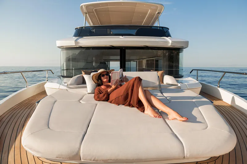  Yacht Photos Pics Woman relaxing on the deck of a 2026 Absolute Navetta 62 yacht, reading.