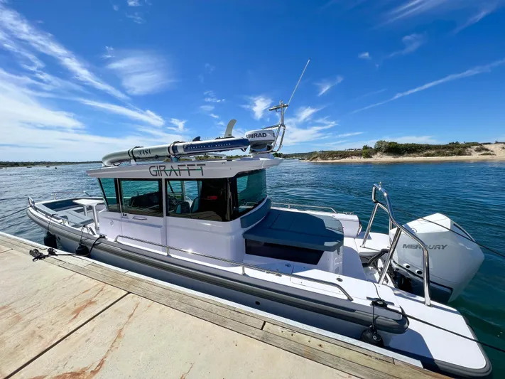 Girafft Yacht Photos Pics 2022 Axopar 28 Cabin Aft Cabin boat docked by the water under a clear blue sky.