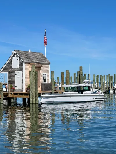 Girafft Yacht Photos Pics 2022 Axopar 28 Cabin Aft Cabin boat docked near a quaint wooden boathouse.
