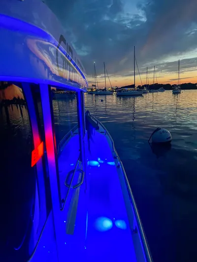 Girafft Yacht Photos Pics 2022 Axopar 28 Cabin Aft illuminated at sunset, docked with sailboats in the background.