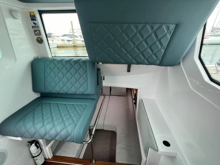 Girafft Yacht Photos Pics 2022 Axopar 28 Cabin Aft Cabin interior with quilted blue seating and window view.