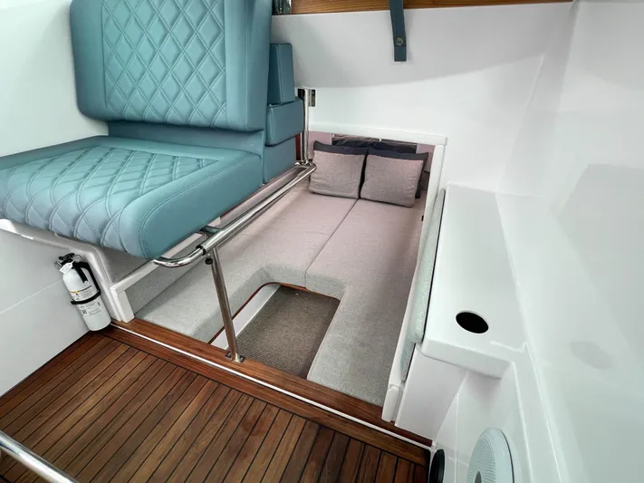 Girafft Yacht Photos Pics 2022 Axopar 28 Cabin Aft Cabin interior with blue seating and wood flooring.
