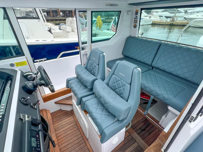 Girafft Yacht Photos Pics 2022 Axopar 28 Cabin Aft Cabin interior with blue seating and wood flooring.