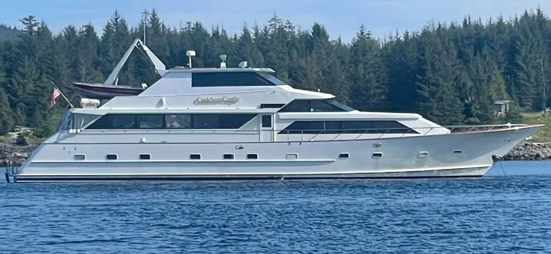 Golden Eagle Yacht Photos Pics 1989 Broward Raised Pilothouse MY yacht on calm water, surrounded by forested landscape.
