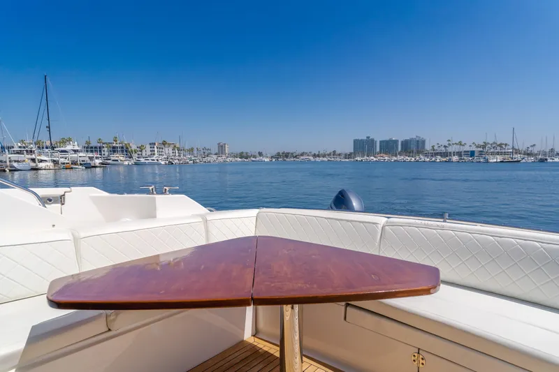 No Regrets Yacht Photos Pics 2016 Sea Ray L590 yacht with a wooden table, overlooking a marina under clear blue skies.
