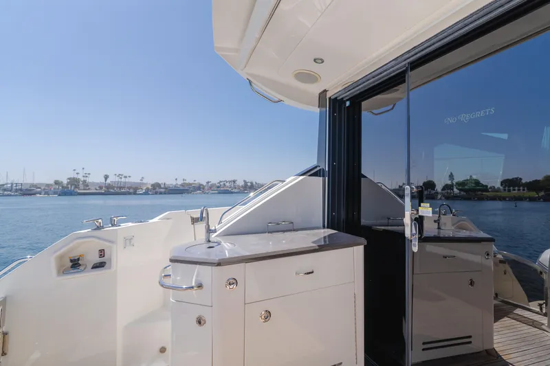 No Regrets Yacht Photos Pics 2016 Sea Ray L590 yacht deck with outdoor kitchen, overlooking serene waterfront.