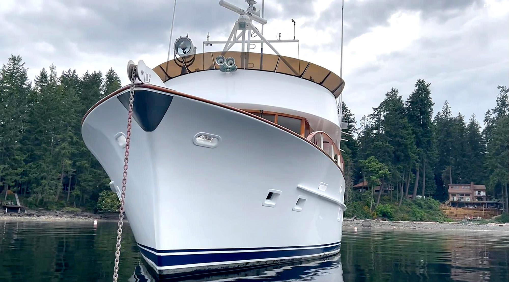 1967 Custom 74 George Moore Passagemaker yacht anchored near forested shoreline.