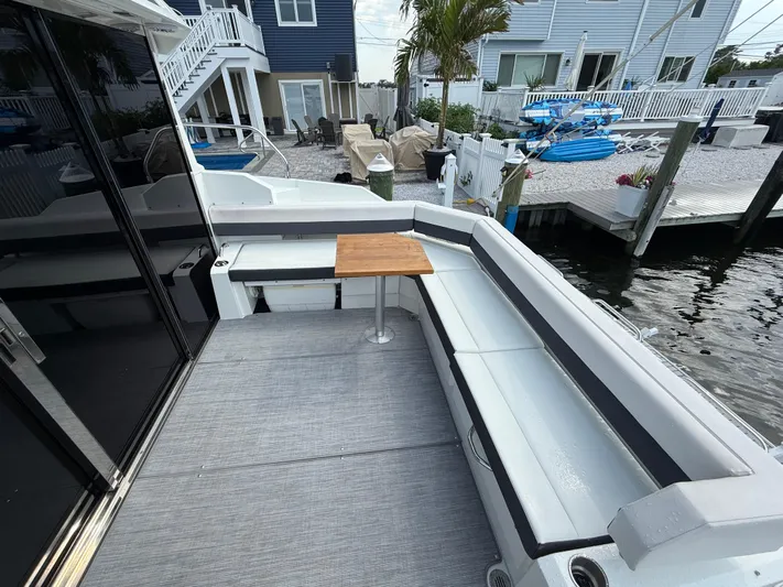  Yacht Photos Pics 2018 Cruisers Yachts 42 Cantius deck with seating and table, docked by waterfront homes.