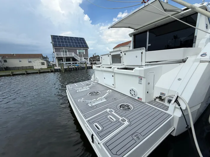  Yacht Photos Pics 2018 Cruisers Yachts 42 Cantius docked near waterfront homes under a cloudy sky.