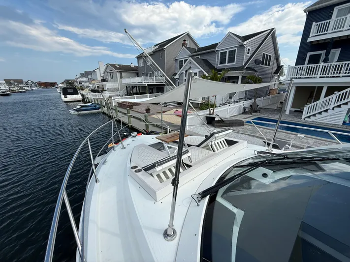  Yacht Photos Pics 2018 Cruisers Yachts 42 Cantius docked near waterfront homes under a partly cloudy sky.