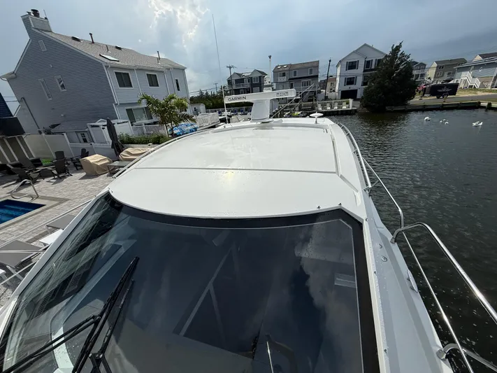  Yacht Photos Pics 2018 Cruisers Yachts 42 Cantius docked near waterfront homes, showcasing sleek design.