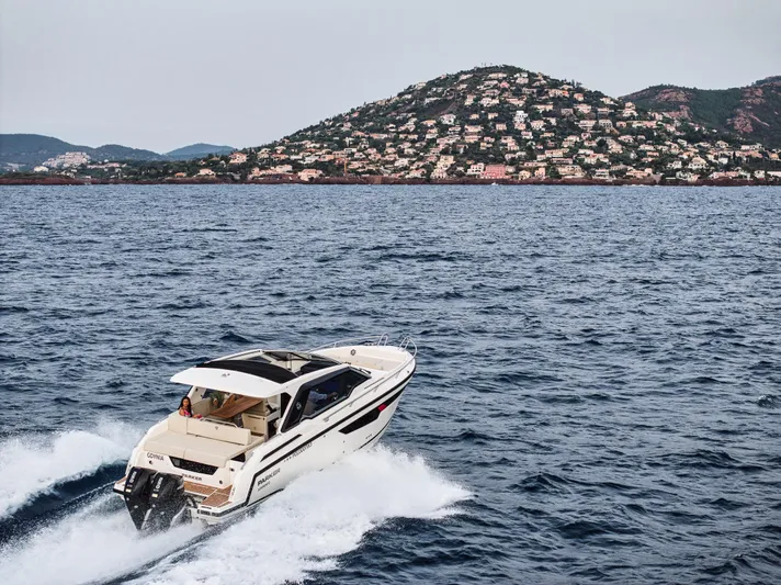  Yacht Photos Pics 2024 Skamander Sorrento boat cruising on the ocean with scenic hillside backdrop.