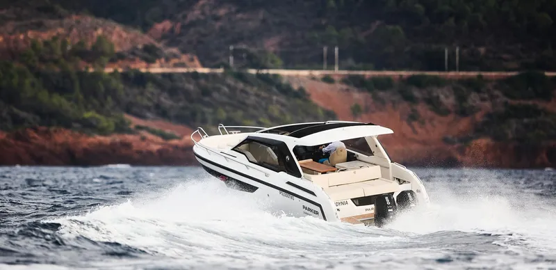  Yacht Photos Pics 2024 Skamander Sorrento boat navigating through waves near a rocky coastline.
