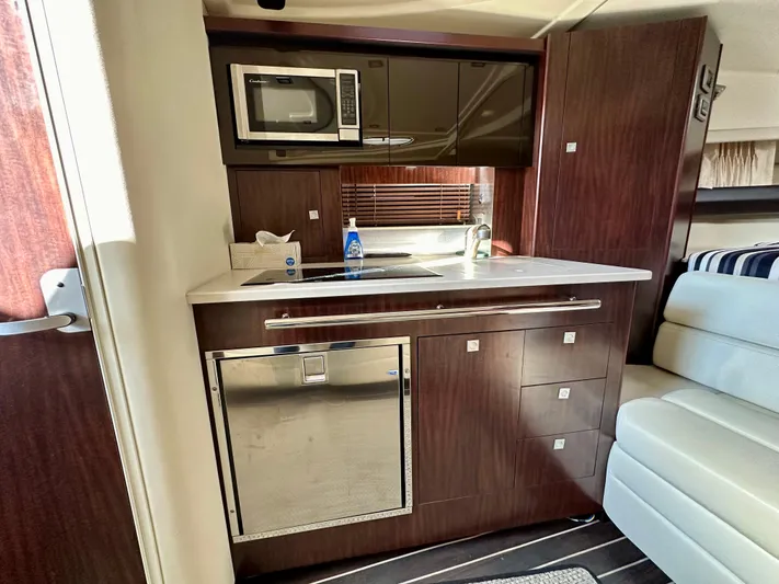 Magic Ten Yacht Photos Pics Compact kitchen area in a 2015 Monterey 335 Sport Yacht with modern appliances and wood cabinetry.