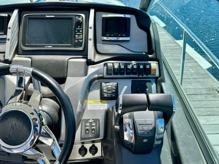 Magic Ten Yacht Photos Pics Control panel of a 2015 Monterey 335 Sport Yacht with steering wheel and navigation screens.