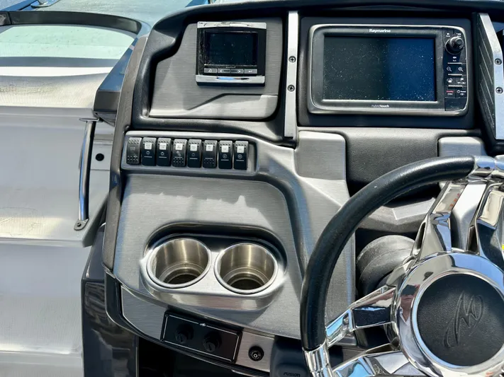 Magic Ten Yacht Photos Pics Control panel of a 2015 Monterey 335 Sport Yacht with steering wheel and navigation screens.