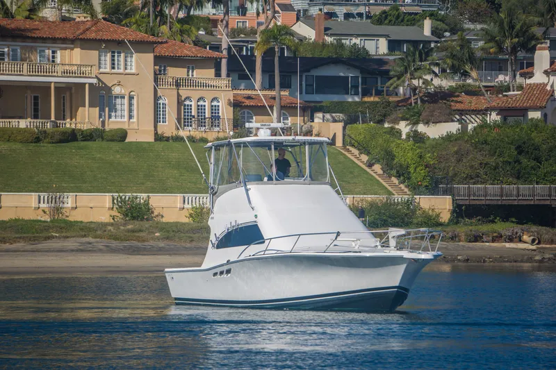 Lost Boys Yacht Photos Pics 2002 Luhrs 36 Convertible yacht cruising near luxurious waterfront homes.