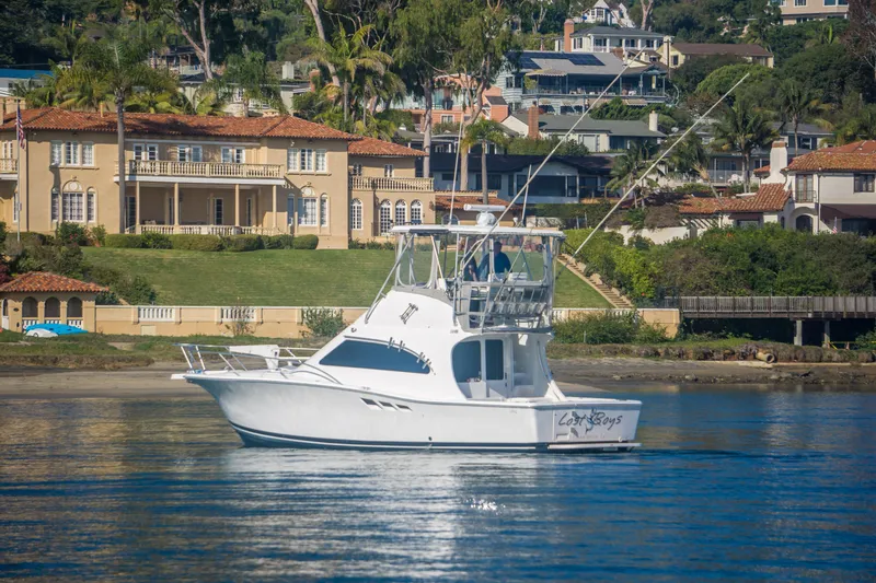Lost Boys Yacht Photos Pics 2002 Luhrs 36 Convertible yacht on calm water near luxury waterfront homes.